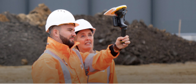 2 people wearing orange workwear using a sitevision device
